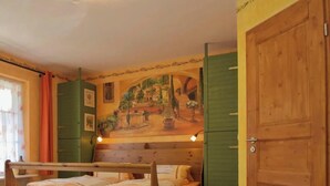 Een houten bed met hoofdeinde, een groene deur en een muurschildering op de muur.