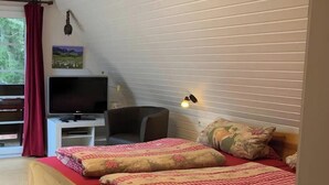 A bedroom with a wooden bed, a television, a desk, and a chair.