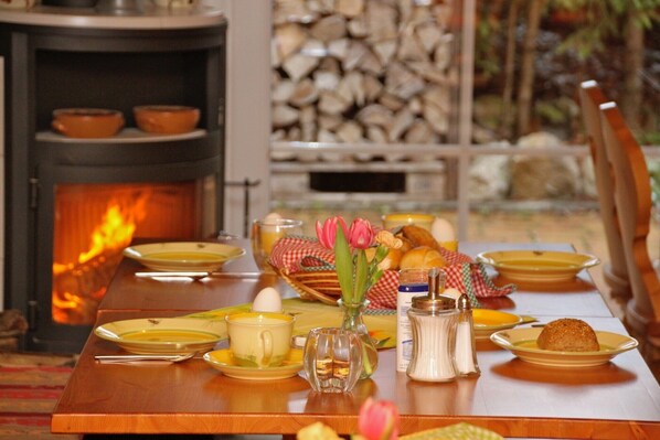 A dining table set with plates, a pitcher, a cup, a vase with flowers, salt and pepper shakers, and a basket of bread. - Room 'Familienzimmer' with Mountain View, Shared Terrace and Wi-Fi (Schluchsee)