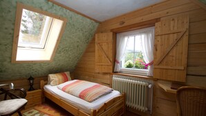Une chambre à coucher avec un lit, une fenêtre, un radiateur et une chaise.