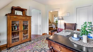 Un comedor con mesa de madera, sillas, alfombra y un aparador con puertas de cristal.