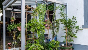 Een tuin met verschillende plantenpotten, een houten trel en een hangplant.