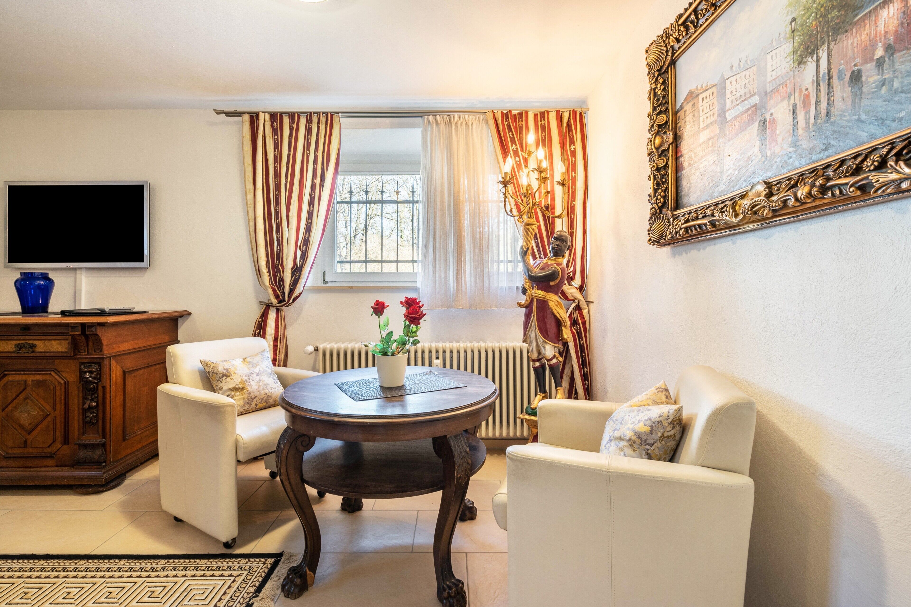 A living room with a sofa, armchair, coffee table, TV, and a painting on the wall.