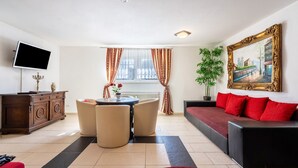 Een woonkamer met een bank, een televisie, een eettafel en een schilderij aan de muur.
