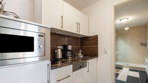 Een moderne keuken met een ingebouwde magnetron, koffiezetapparaat en vaatwasser.