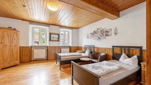 Ein Schlafzimmer mit zwei Betten, Holzböden, einem Heizkörper und einem Fenster.