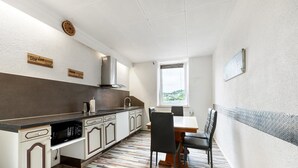 A modern kitchen with a microwave, stove, and sink; a dining area with a table and chairs; and a view of greenery outside.