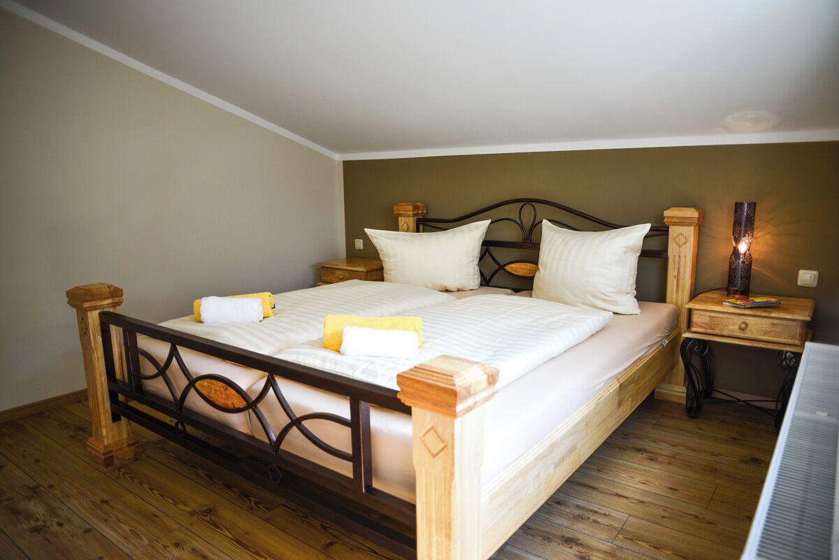 A single bed with a wooden frame, two nightstands, and a bedside lamp.