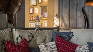 A cozy living room with a sofa adorned with patterned cushions, a decorative wall with framed pictures, and a rustic wooden panel. - Apartment Central Leipzig-Zoo (Leipzig)