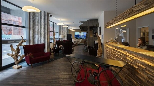 A modern hotel lobby with a reception desk, seating area, and large windows. - Apartment Central Leipzig-Zoo (Leipzig)