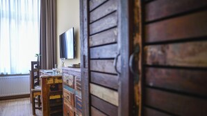 A room with a wooden dresser, a television on the wall, and a window with curtains. - Apartment Central Leipzig-Zoo (Leipzig)