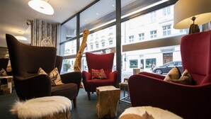 A modern interior with a large window, red armchairs, and a wooden tree stump. - Apartment Central Leipzig-Zoo (Leipzig)