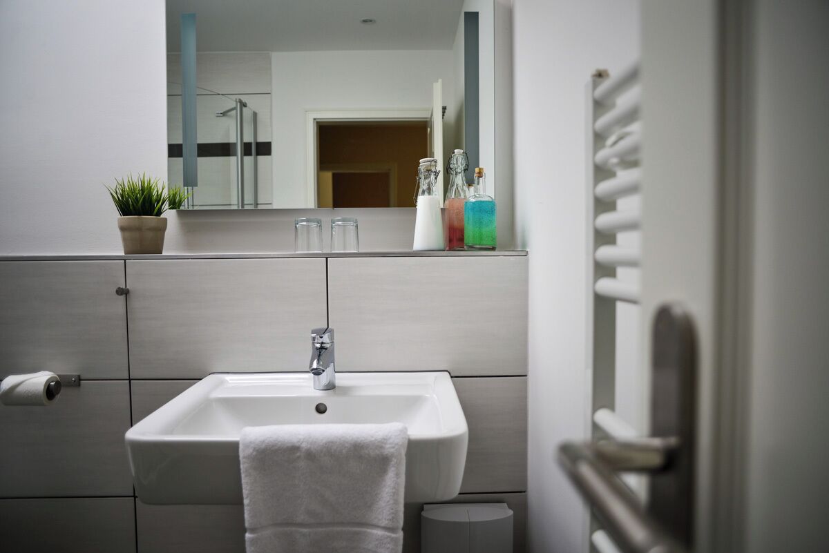 A modern bathroom with a white sink, a towel hanging on the wall, and a mirror above the sink.