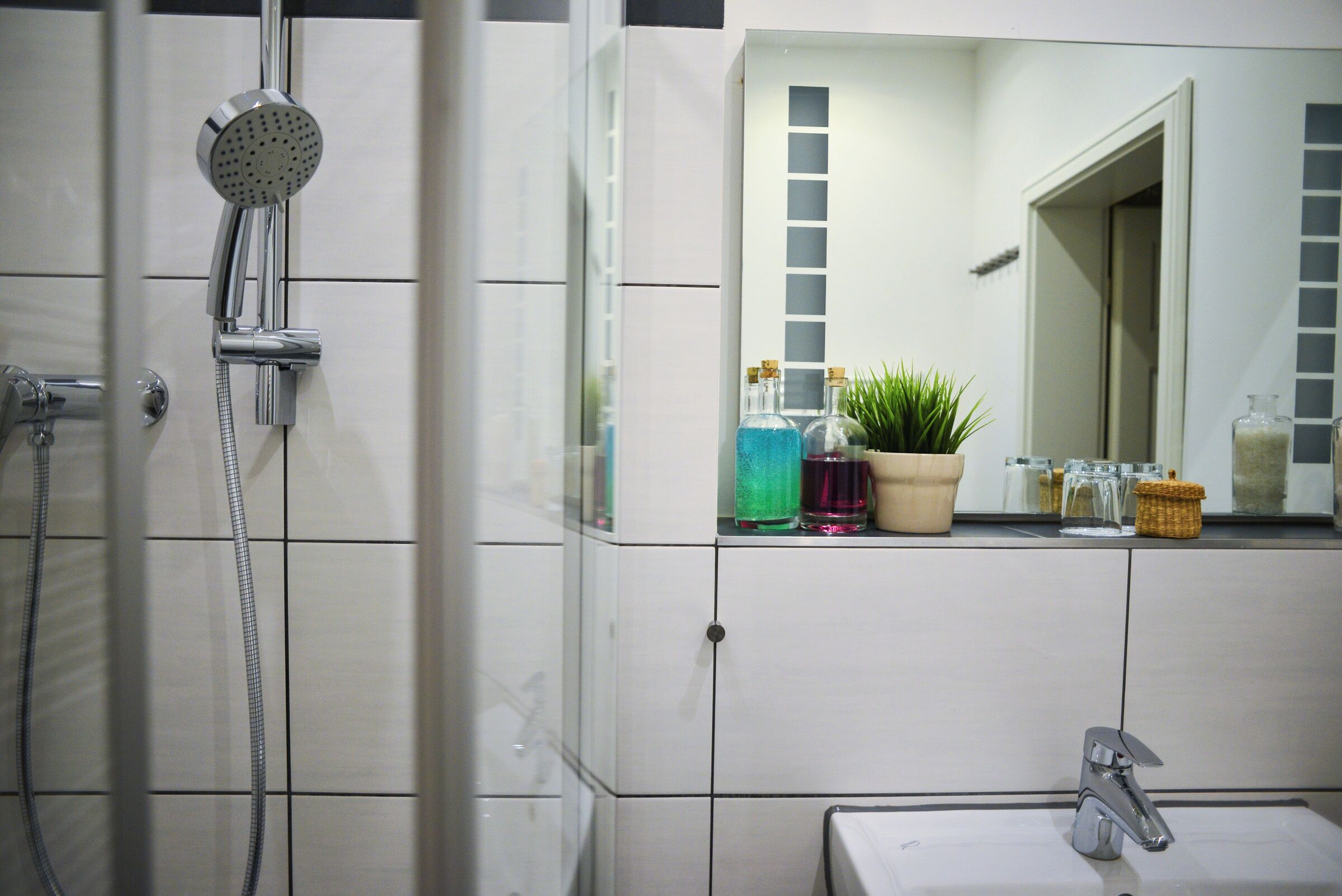 A bathroom with a shower, sink, and mirror.