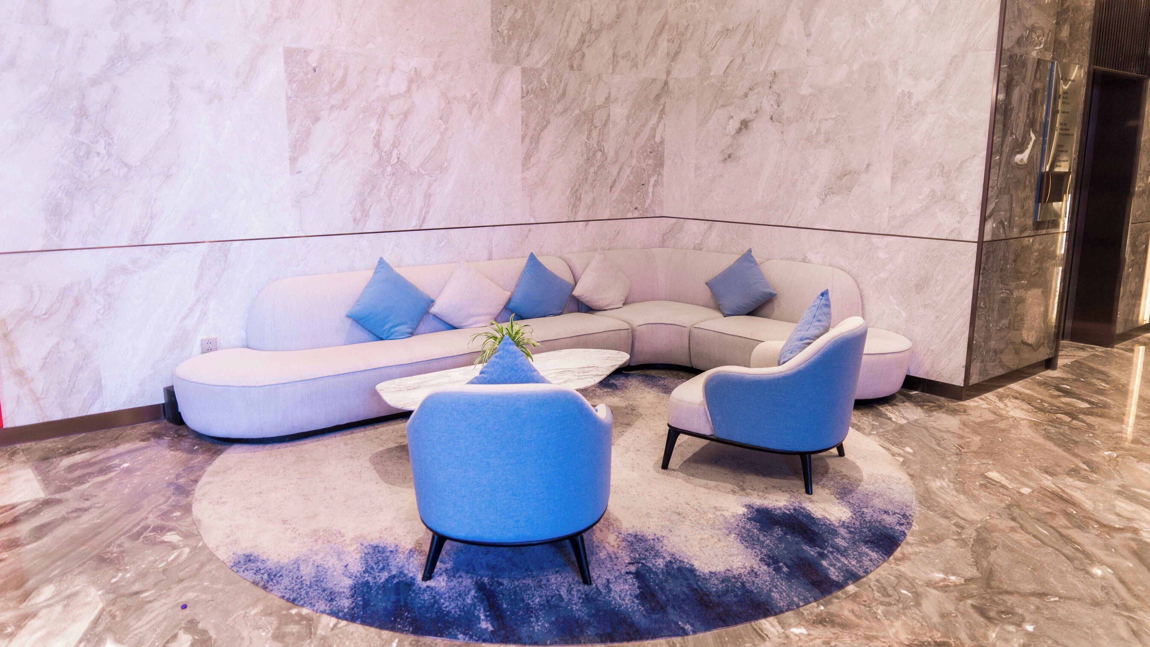 Ein moderner Lounge-Bereich mit einer gebogenen Couch, zwei Sesseln und einem Couchtisch.