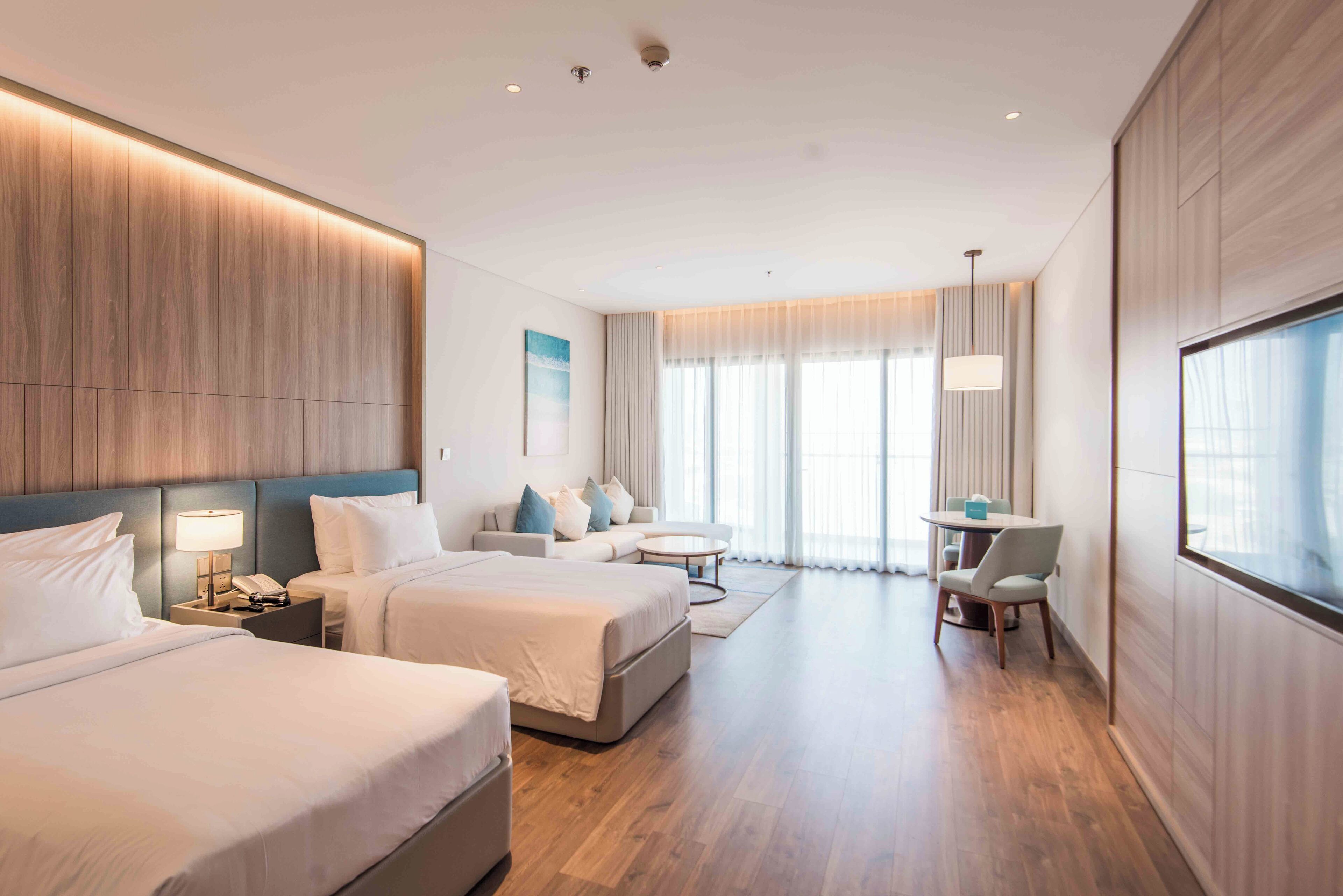 Et moderne hotelværelse med to senge, en sofa, et lille bord og et skrivebord.
