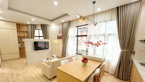 Una sala moderna con televisor, sofá, mesa de comedor y un amplio ventanal con cortinas.