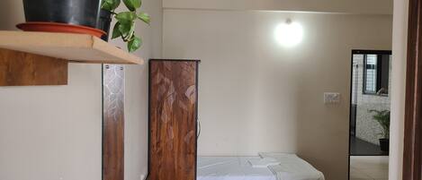 Habitación de hotel con dos camas, ventilador de techo, planta en maceta y espejo.