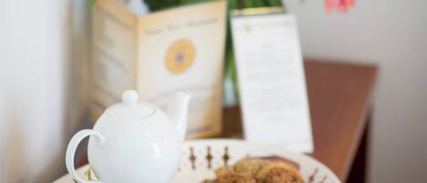 A tray with a teapot, two cups of tea, and cookies on a table.