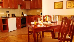 Una cocina compacta con armarios de madera, una mesa de comedor con sillas y productos para el desayuno sobre la mesa.