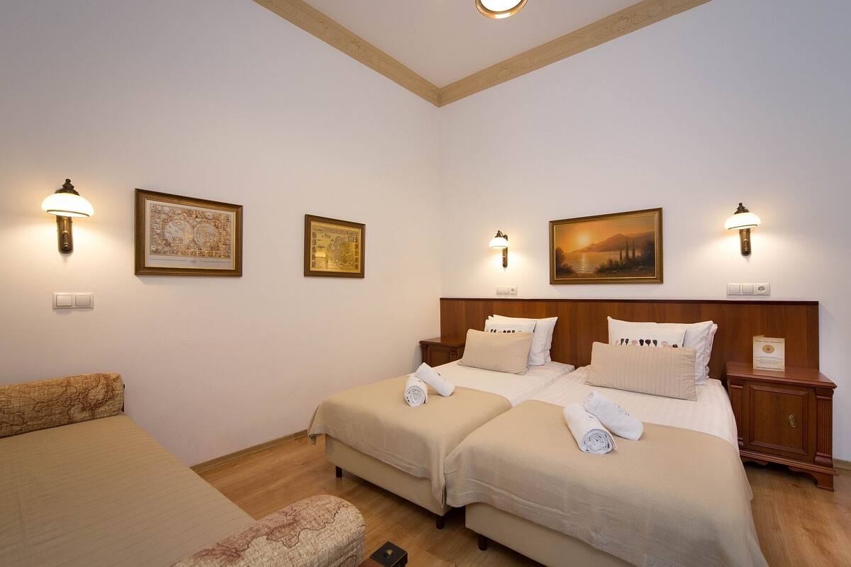 Quarto de hotel com duas camas, um sofá e obras de arte nas paredes.