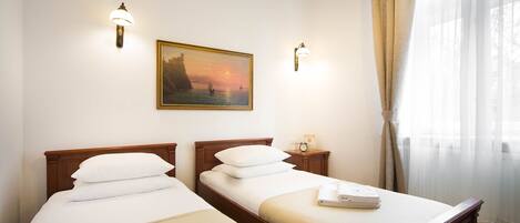 A hotel room with two single beds, a painting on the wall, and a window with curtains.