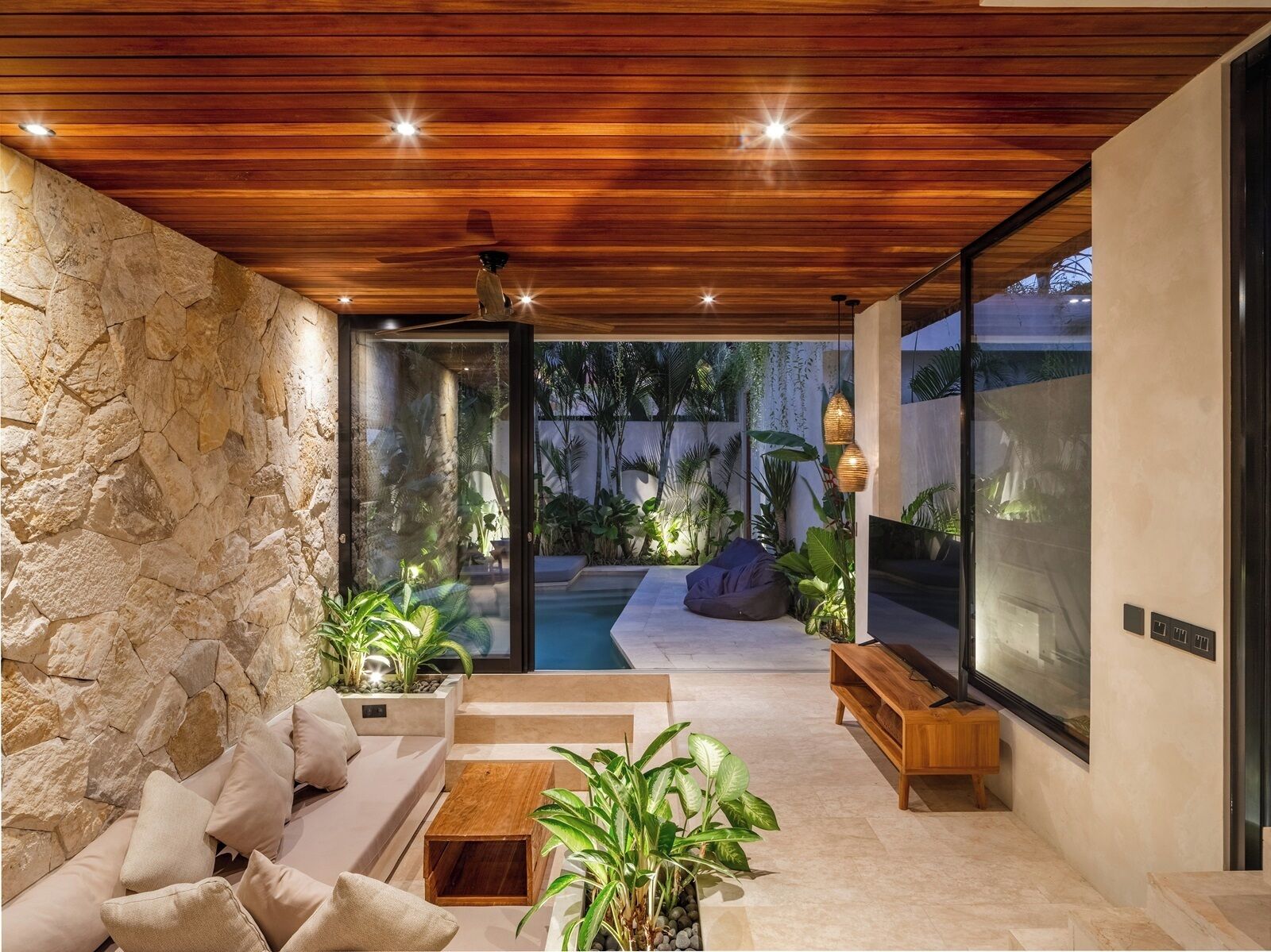 Ein moderner Außenbereich mit Steinwand, Holzboden und einem Pool.