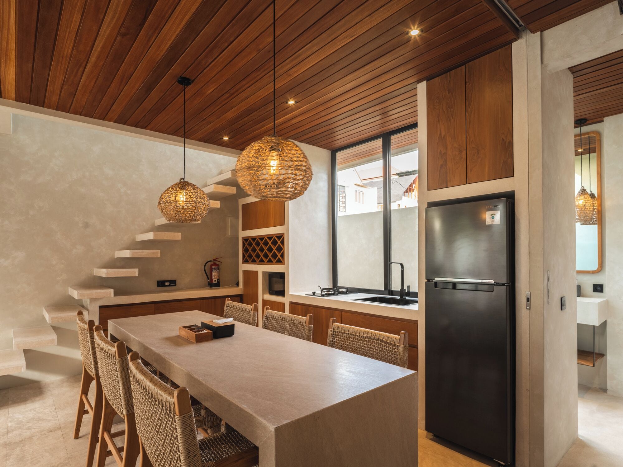 A modern kitchen with a central island, wooden ceiling, and built-in appliances.
