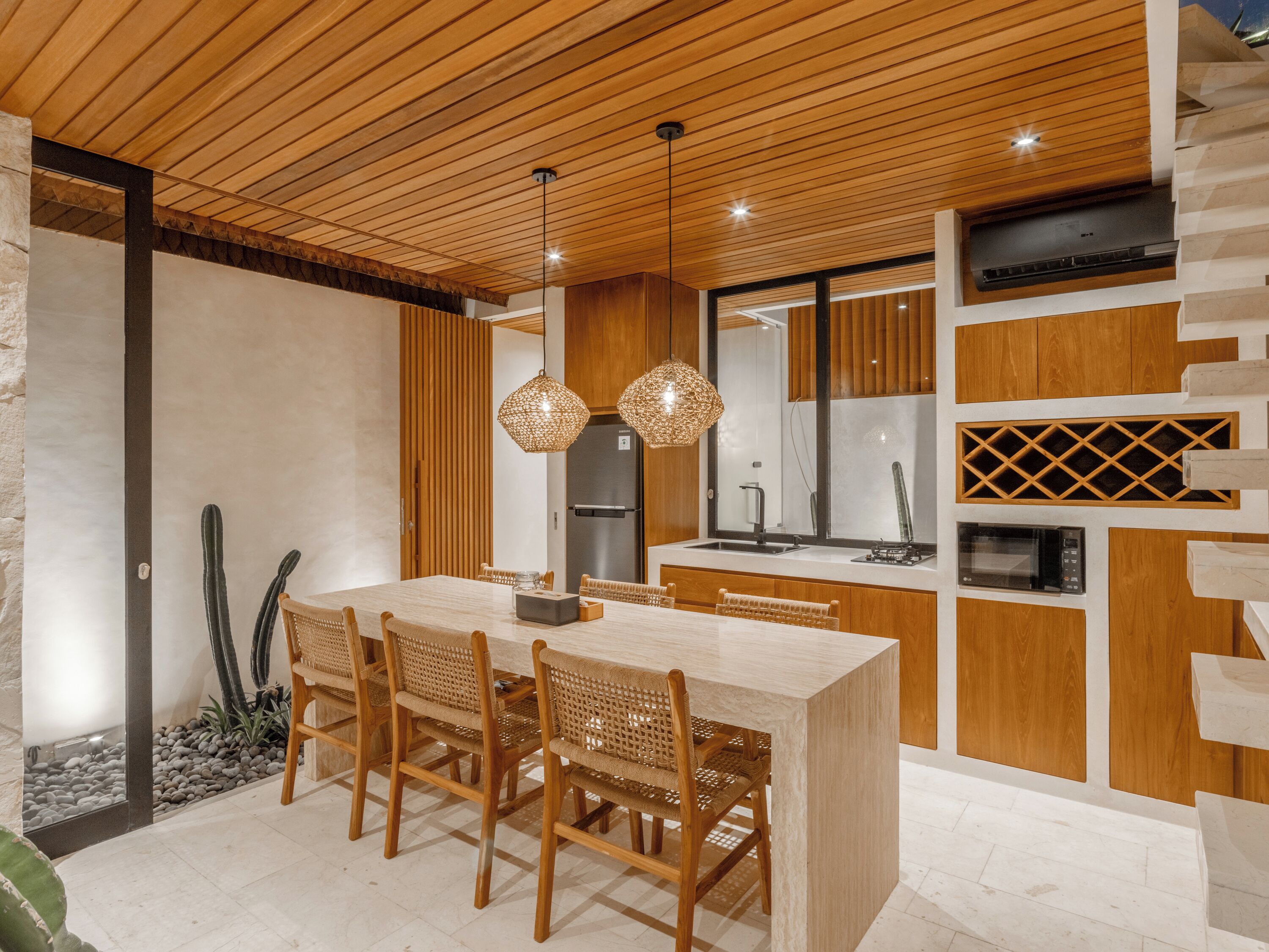 Une cuisine moderne avec des meubles en bois, un îlot central et des luminaires suspendus.