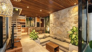 Un interior moderno con techo de madera, pared de piedra y sofá modular.