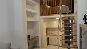 A modern living room with a wooden coffee table, a sofa, and a staircase leading to a kitchen area. - Corfu Luxury Loft2 by Corfuescapes (Corfu)