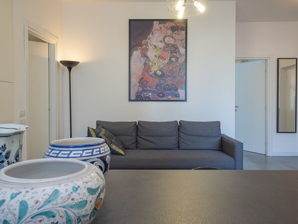 A modern living room with a grey sofa, a large abstract painting, and decorative vases.