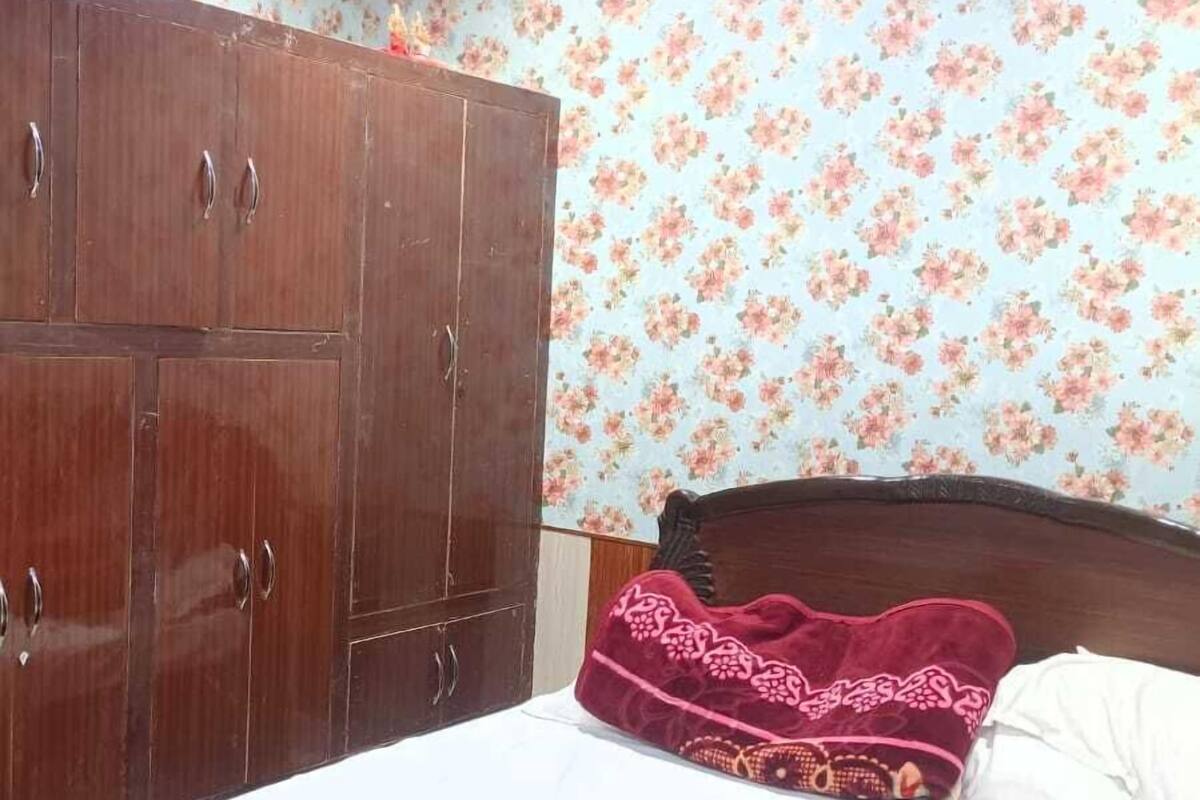 A bedroom with a bed, a wardrobe, and floral wallpaper.