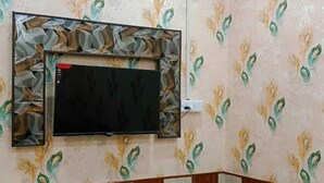 Une chambre d’hôtel avec un lit, un téléviseur fixé au mur et un papier peint à motifs.