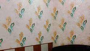 Une chambre à coucher avec un lit, une tête de lit et un mur orné d’un motif floral.