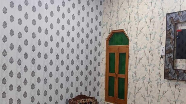 Une chambre à coucher avec un lit, une chaise, une fenêtre et un papier peint à motifs.