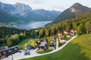Eine Gruppe Holzhäuser mit See und Bergen im Hintergrund.