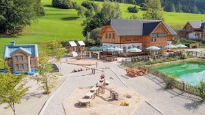 A wooden building with a sign reading "Zoe's Well" and a pool area with tables and umbrellas. - Chalet near Lake Grundlsee & Ski Lift (Grundlsee)