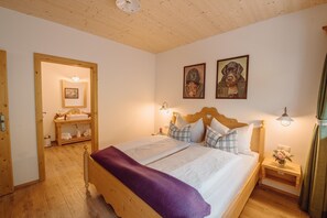 Un dormitorio acogedor con una cama de madera, una mesita de noche con un jarrón de flores y dos cuadros en la pared.