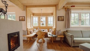 Un salon chaleureux avec une cheminée, des meubles en bois et de grandes fenêtres.