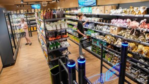 A grocery store aisle with shelves stocked with various products and a person shopping. - Luxuszelt im Serengeti Park (Hodenhagen)