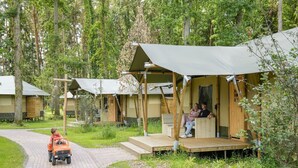 Un hilera de cabañas de madera con porches abiertos, rodeadas por un área boscosa.