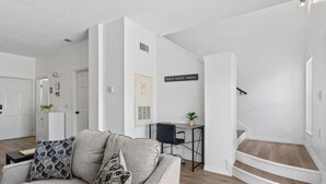 A modern living room with a grey sofa, a small desk, and a staircase. - Amazing 3BR 2BA Townhome With Lake View at Terra Verde! (Kissimmee)