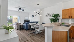 A modern kitchen with a dining area, wooden cabinets, and a ceiling fan. - Amazing 3BR 2BA Townhome With Lake View at Terra Verde! (Kissimmee)