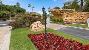 A landscaped area with a rock formation labeled "Terra Verde," a street lamp, and a road. - Amazing 3BR 2BA Townhome With Lake View at Terra Verde! (Kissimmee)