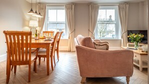 Ein gemütliches Wohnzimmer mit einem Holzesstisch, Stühlen, einer Couch und einem Fernseher.