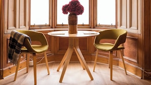 A room with wooden paneled walls, a round table with two chairs, and a vase with flowers. - JOIVY Contemporary Cottage with Parking (Edinburgh)