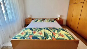 Een slaapkamer met een bed, twee nachtkastjes, een kledingkast en een raam met gordijnen.