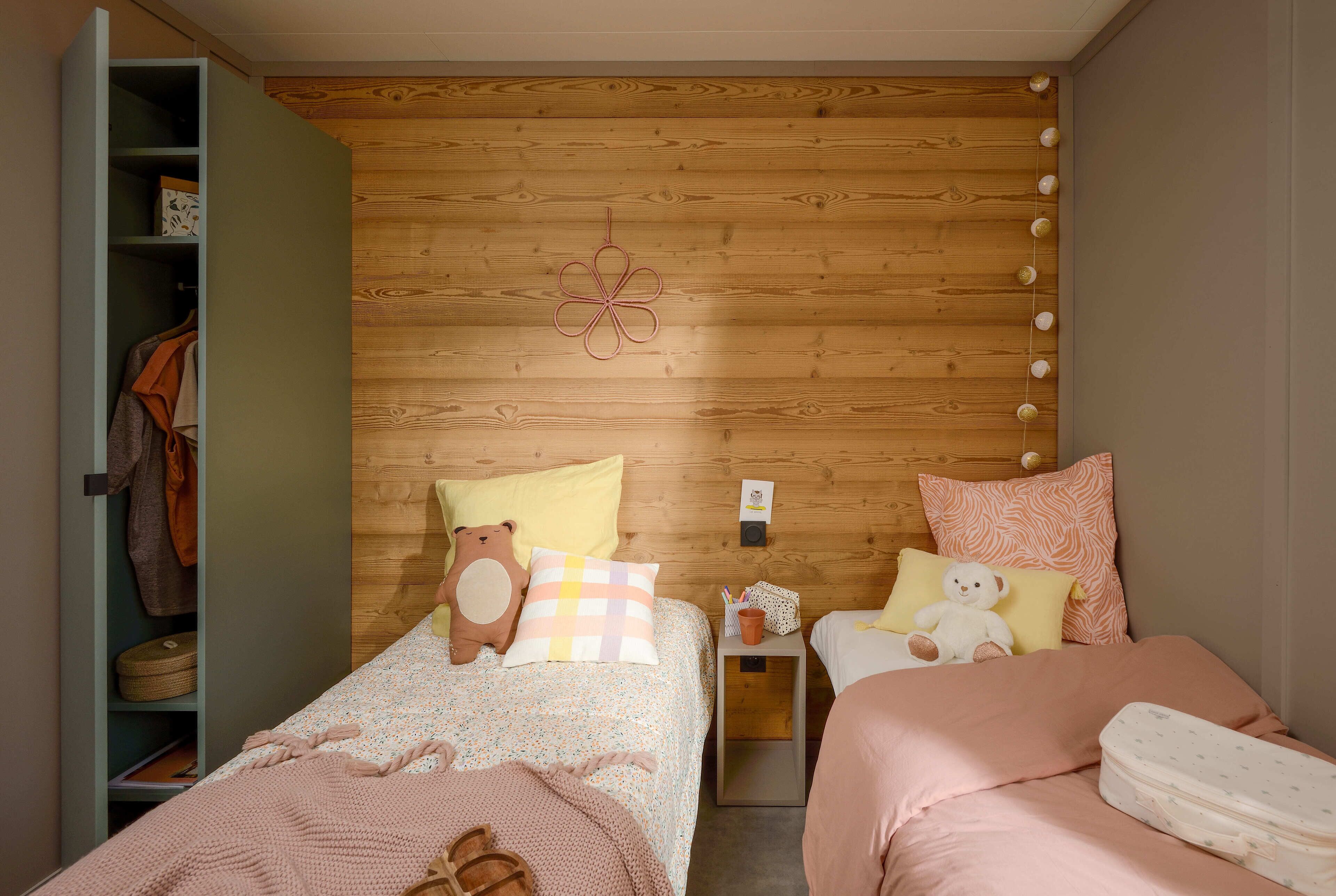 A bedroom with a wooden headboard, two beds, a nightstand, and a wardrobe.