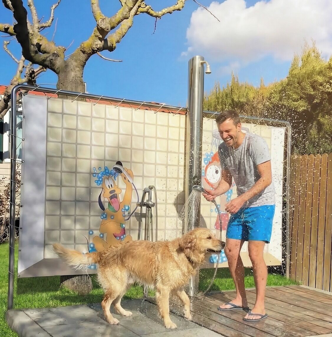 Un homme et un chien se trouvent dans un espace douche, avec un mur carrelé et un pommeau de douche.